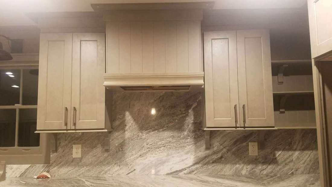 A kitchen with white cabinets and granite counter tops.