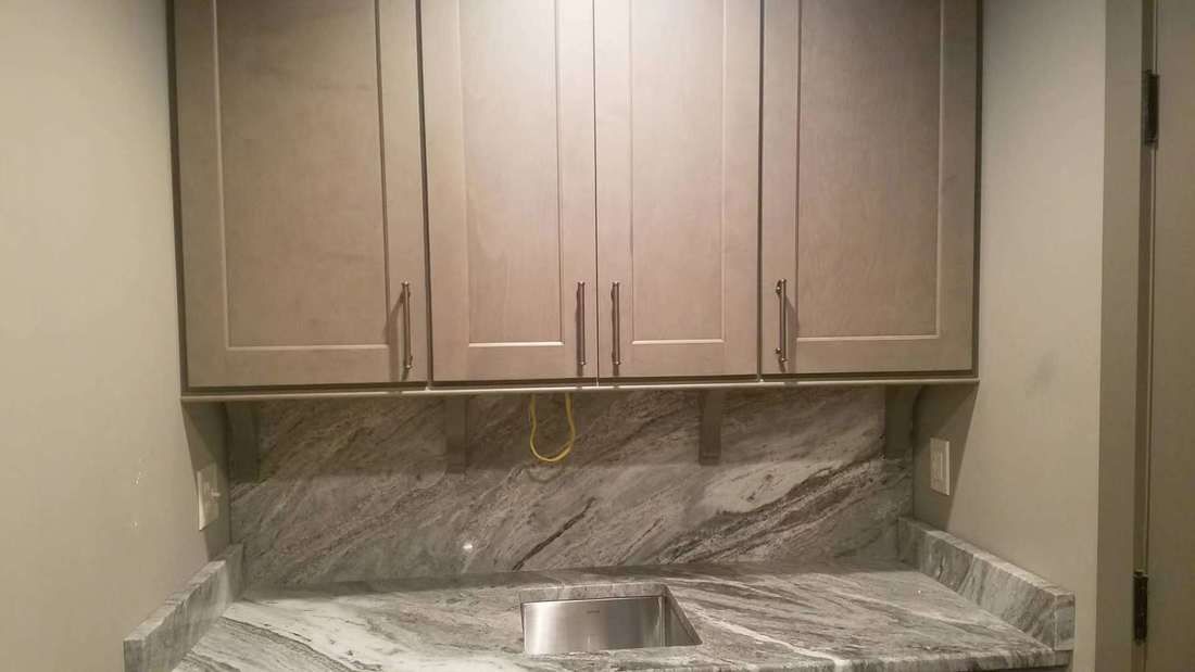 A kitchen with a sink , cabinets and granite counter tops.