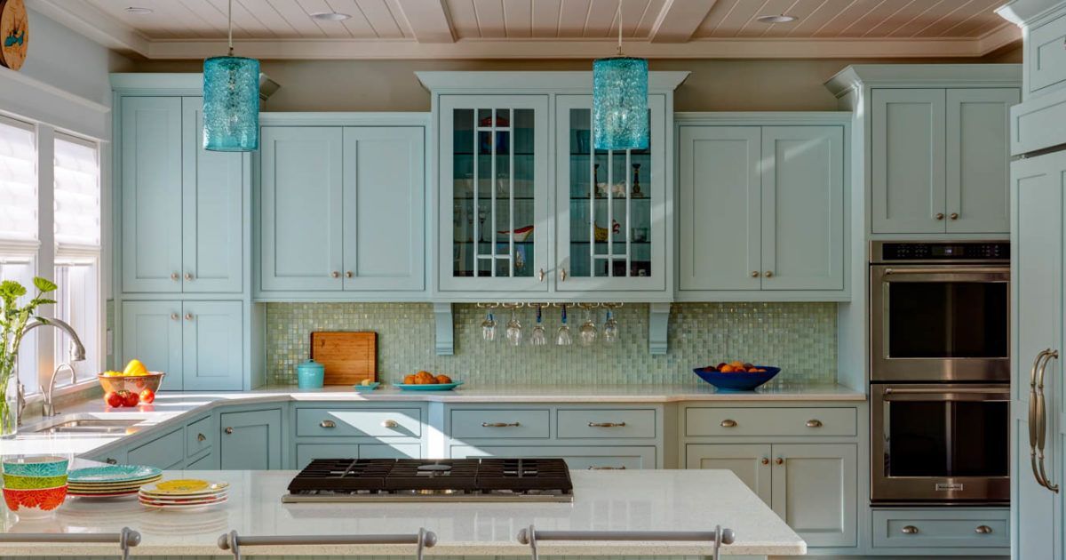 A kitchen with blue cabinets , white counter tops , stainless steel appliances and a large island.