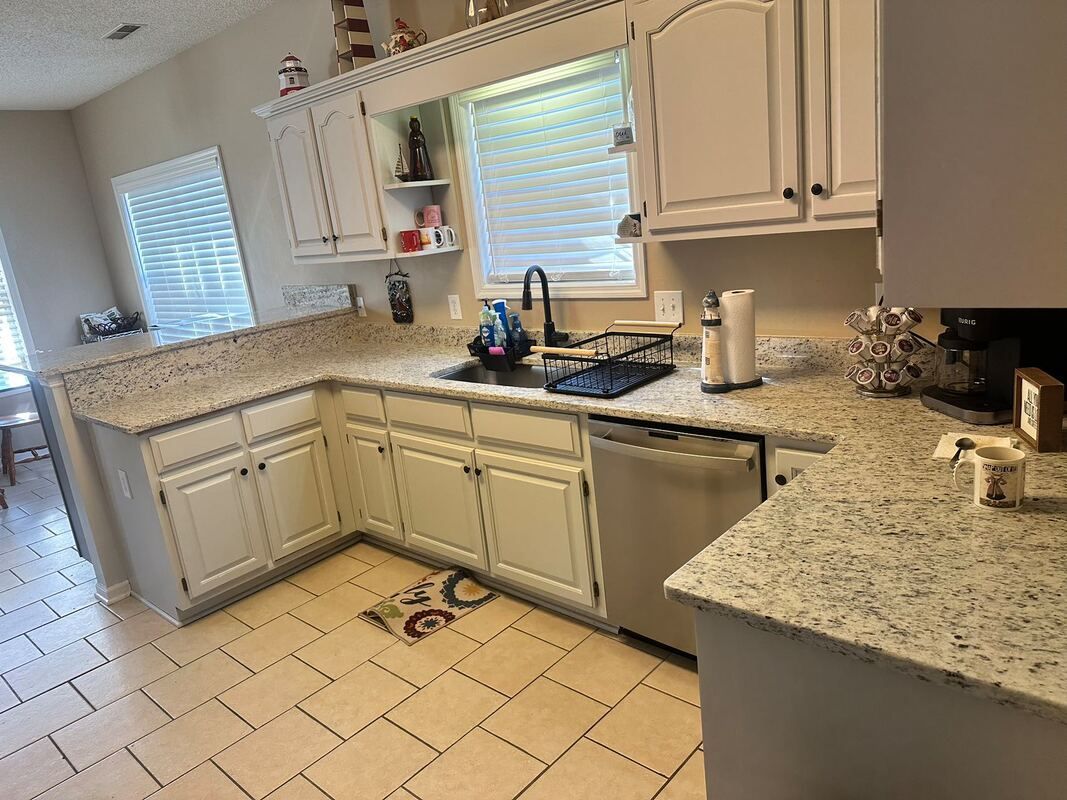 A kitchen with white cabinets and granite counter tops.
