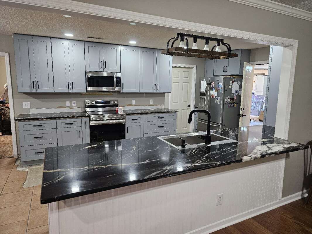 A kitchen with a large island , sink , stove and refrigerator.