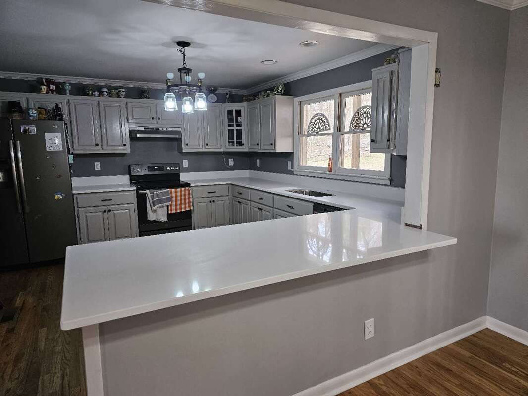 A kitchen with white cabinets and a white counter top.