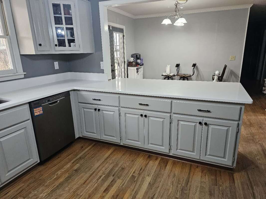 A kitchen with white cabinets , a stainless steel dishwasher , and a large island.