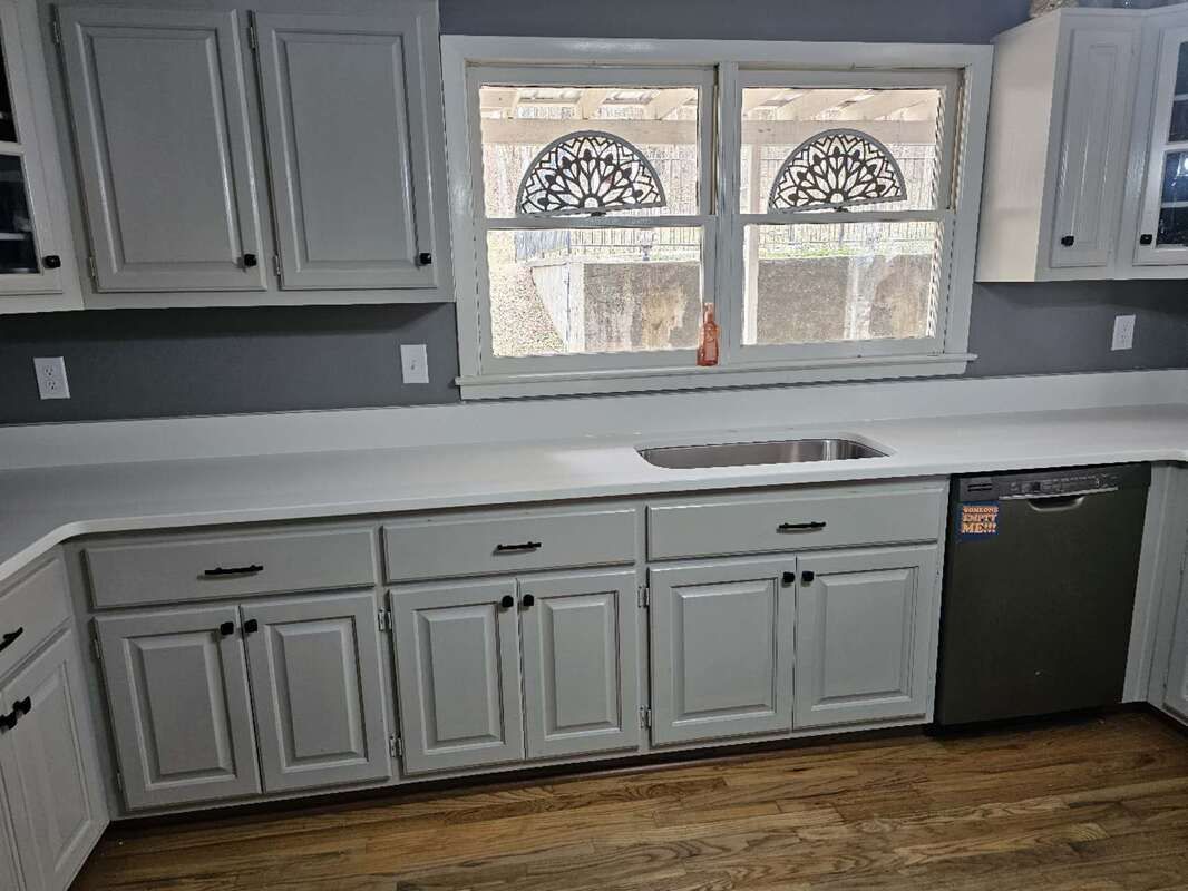 A kitchen with white cabinets , a sink , and a dishwasher.