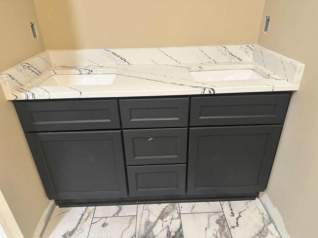 A bathroom vanity with two sinks and a marble counter top.