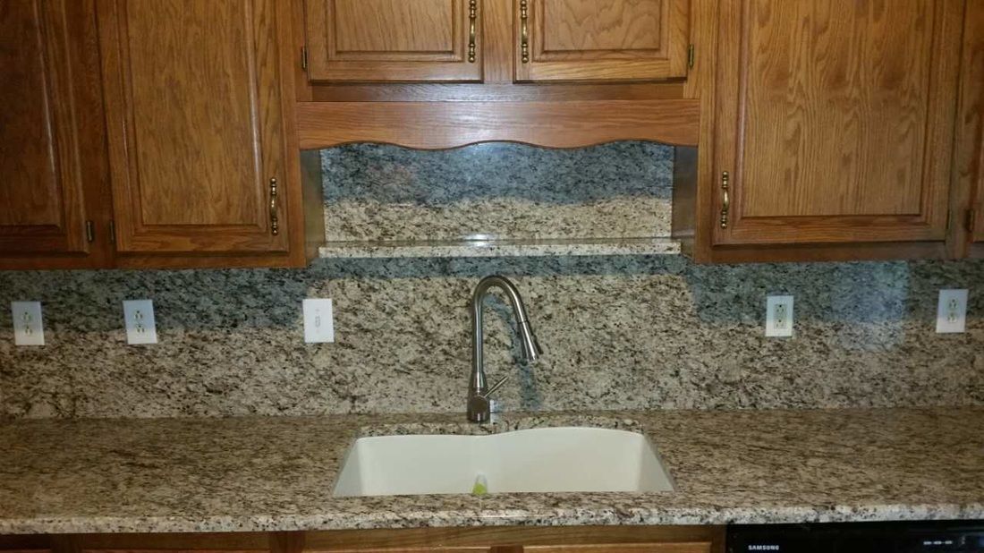 A kitchen sink with granite counter tops and wooden cabinets.