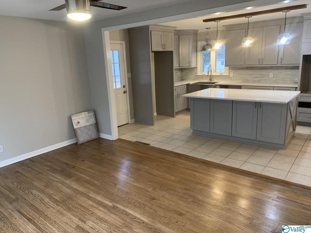A living room with hardwood floors and a kitchen with a large island.