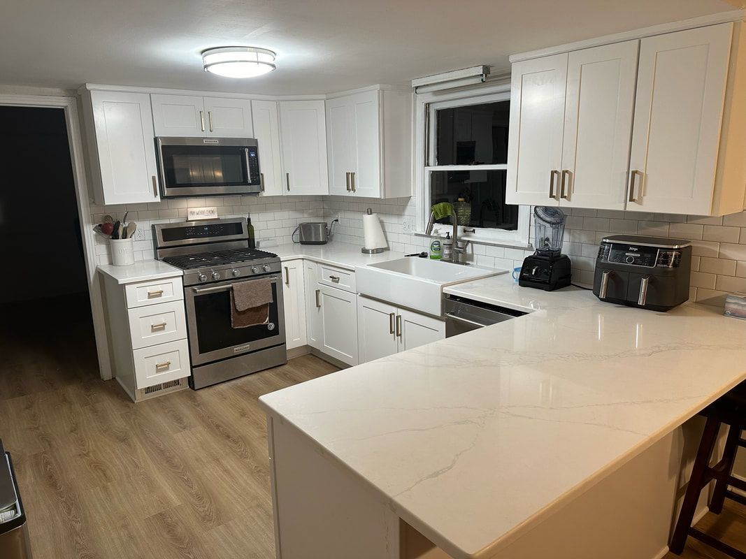 A kitchen with white cabinets , stainless steel appliances , a sink , and a stove.