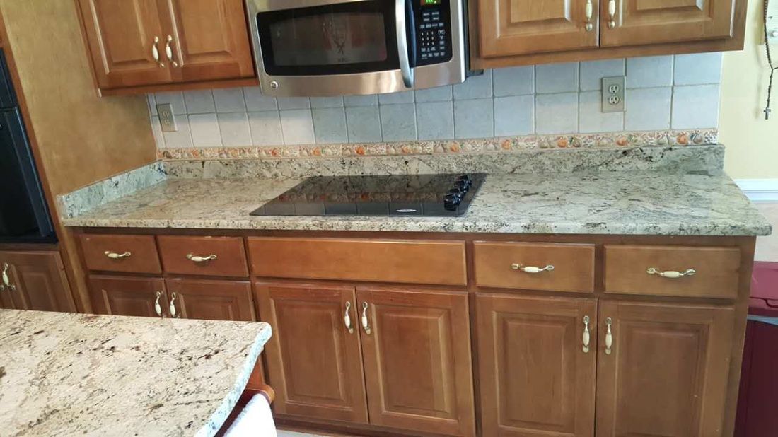 A kitchen with wooden cabinets , granite counter tops , a microwave , and a stove.