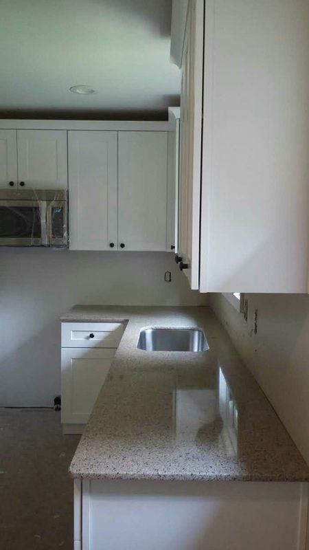 A kitchen with white cabinets and granite counter tops