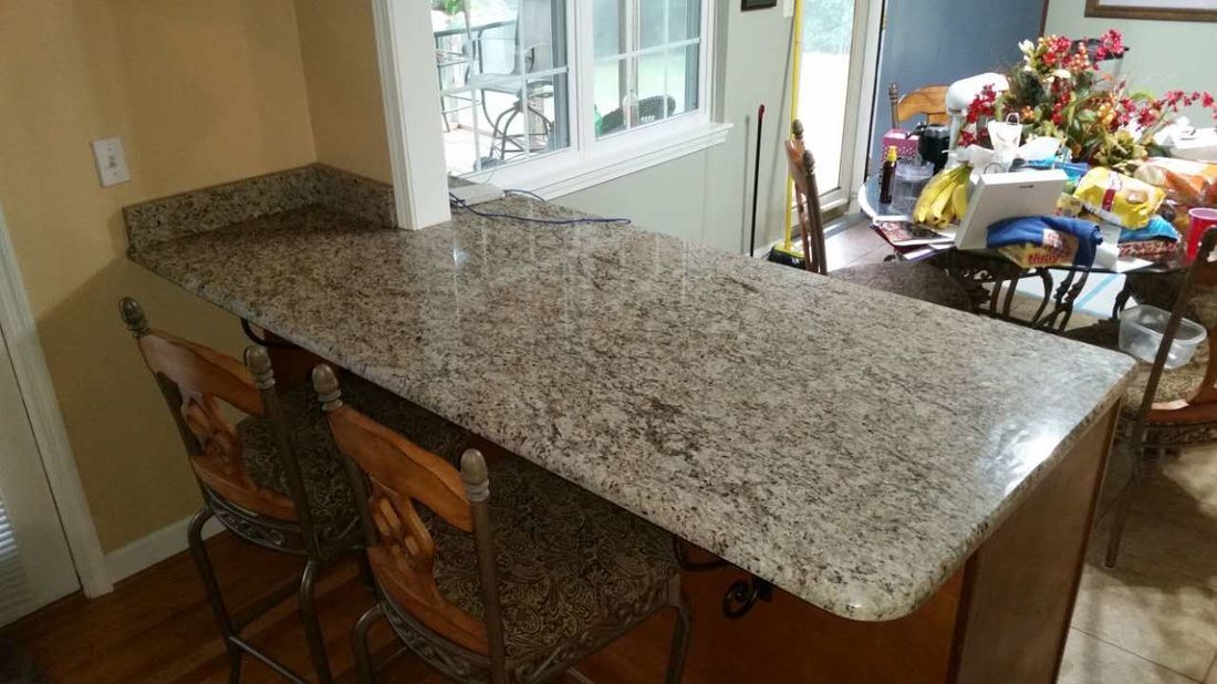 A kitchen with a granite counter top and stools.