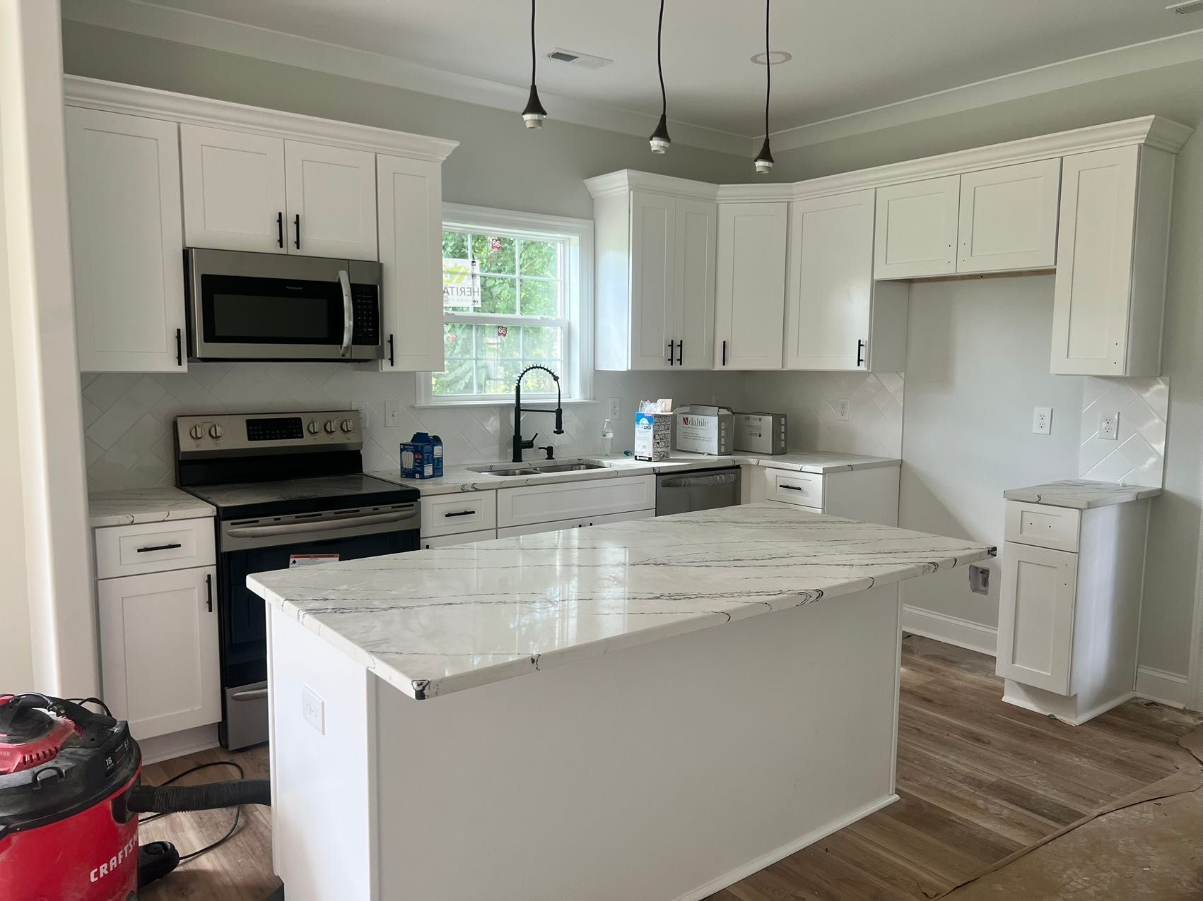 A kitchen with white cabinets , granite counter tops , stainless steel appliances , and a large island.