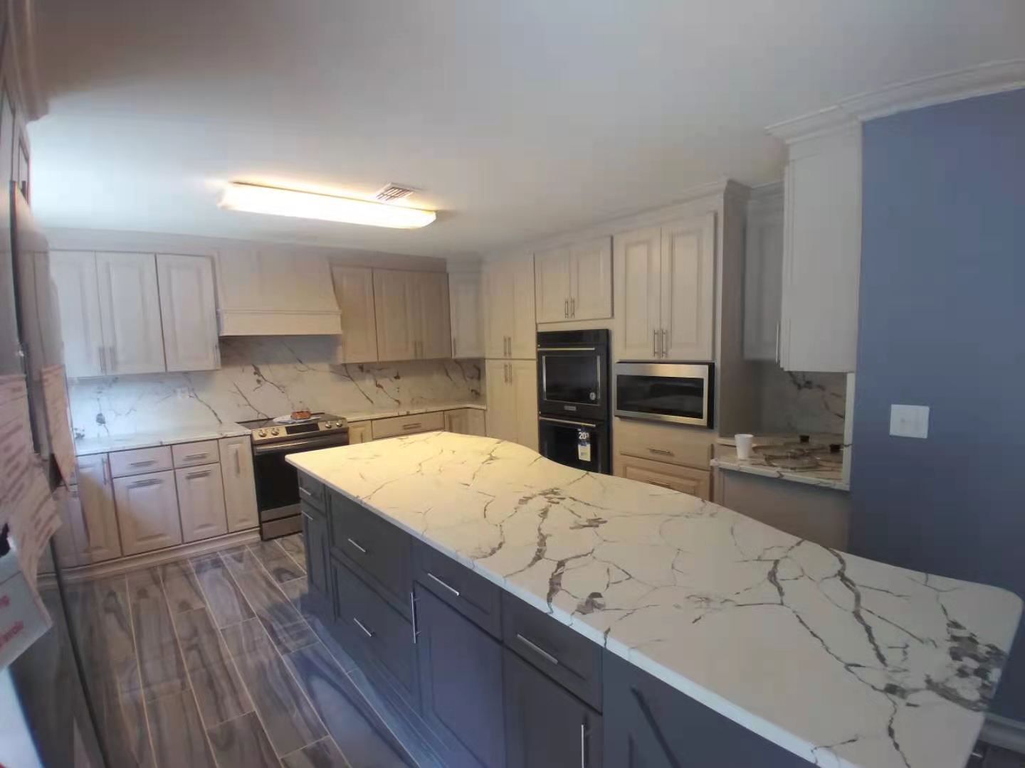 A kitchen with a large island and marble counter tops.