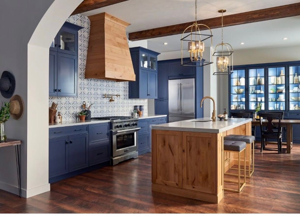 A kitchen with blue cabinets , stainless steel appliances , and a large island.