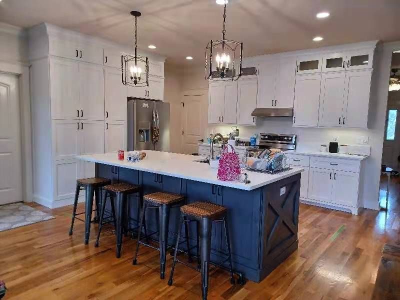 A kitchen with white cabinets and a large island with stools.