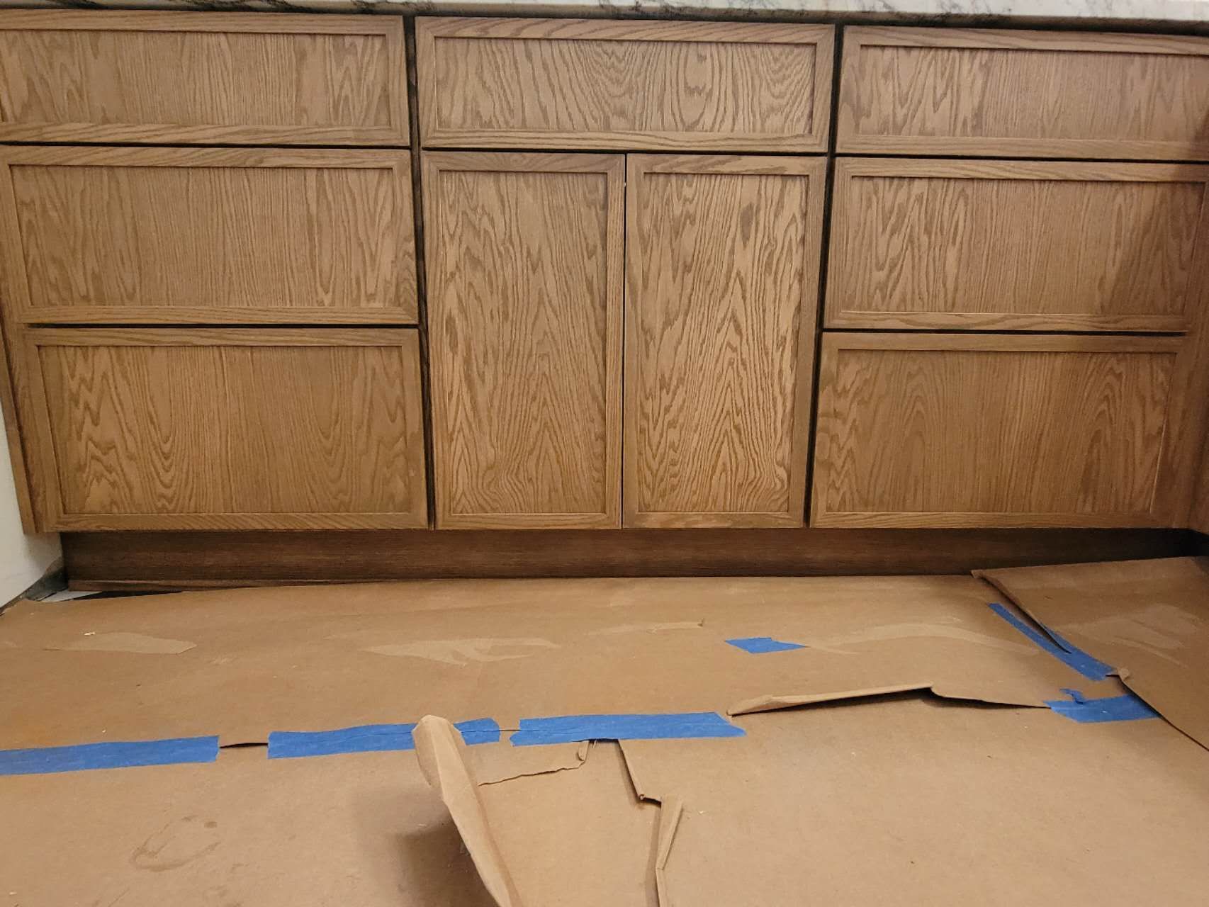 A cardboard box is placed on the floor in front of a wooden cabinet.