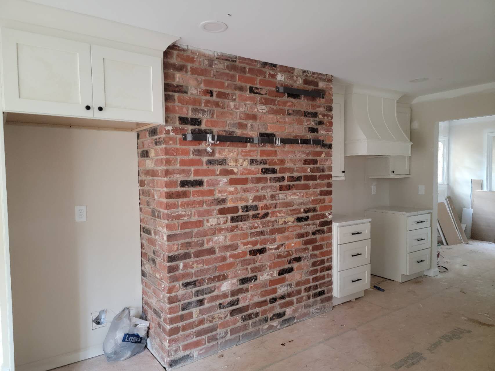 A kitchen with a brick wall and white cabinets.