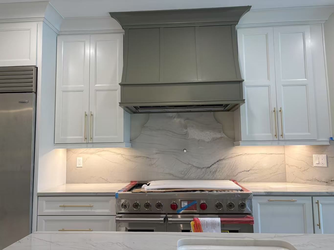 A kitchen with white cabinets and a stove top oven.