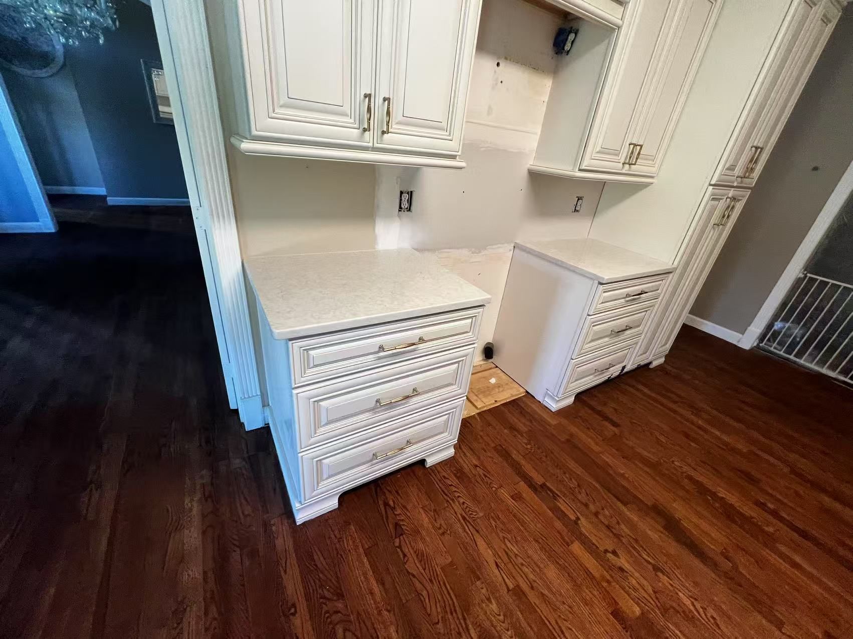 A kitchen with white cabinets and hardwood floors.