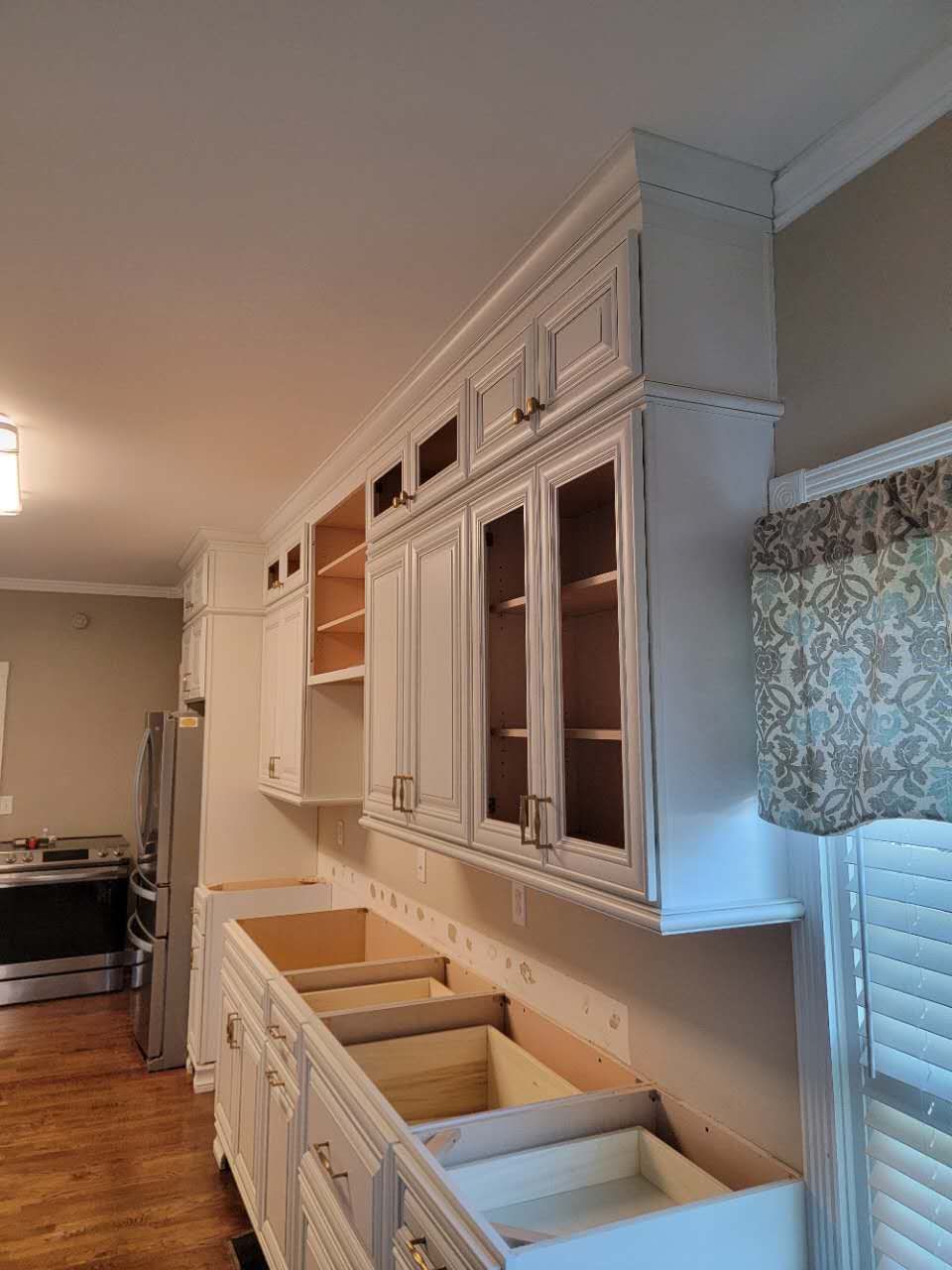 A kitchen with white cabinets and drawers and a window.