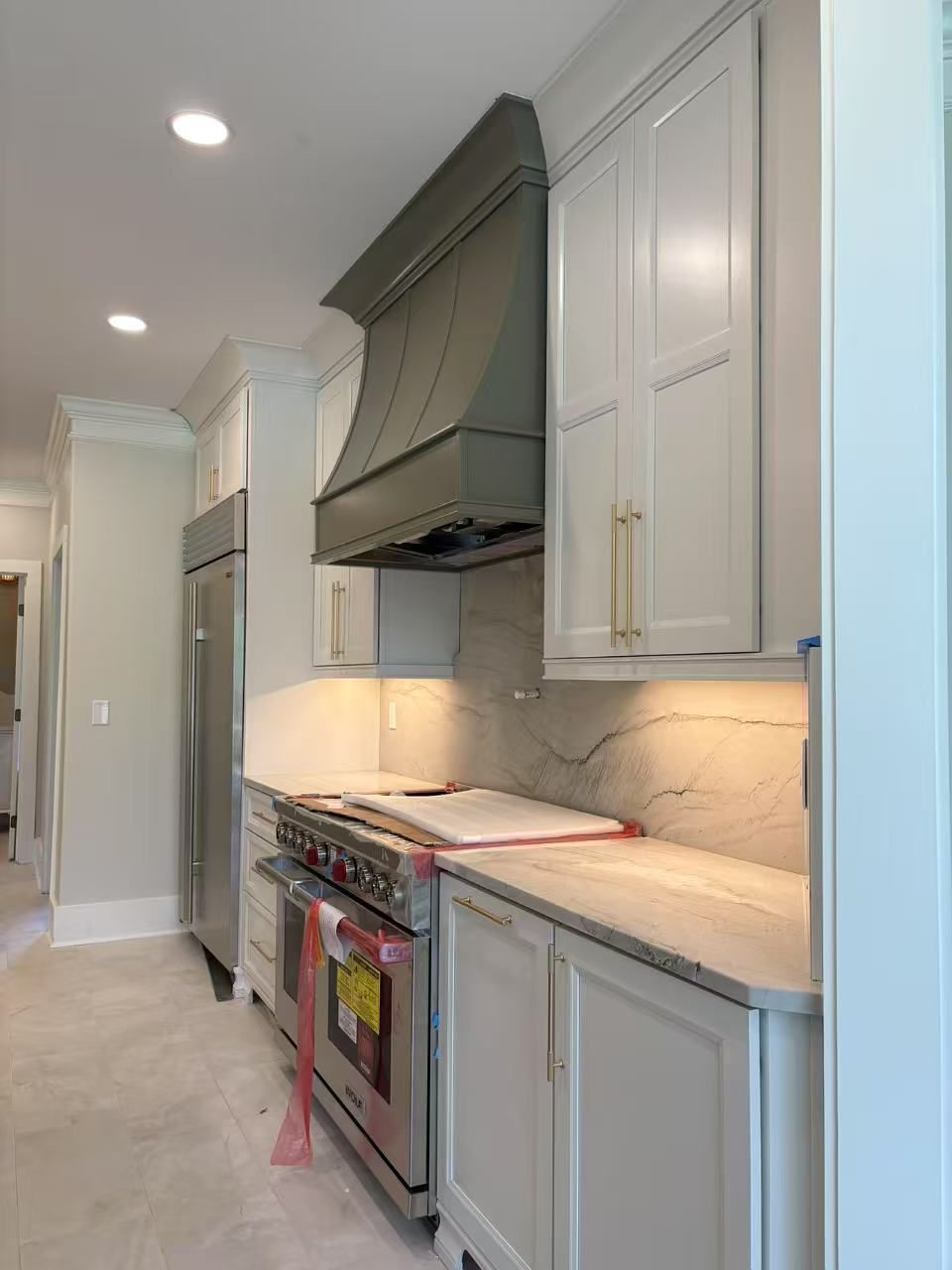 A kitchen with white cabinets, stainless steel appliances, a stove and a refrigerator.