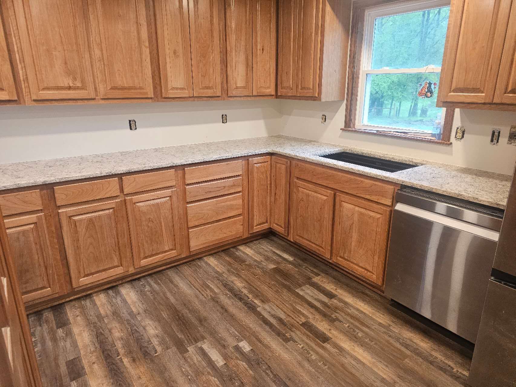A kitchen with wooden cabinets, granite counter tops, and stainless steel appliances.