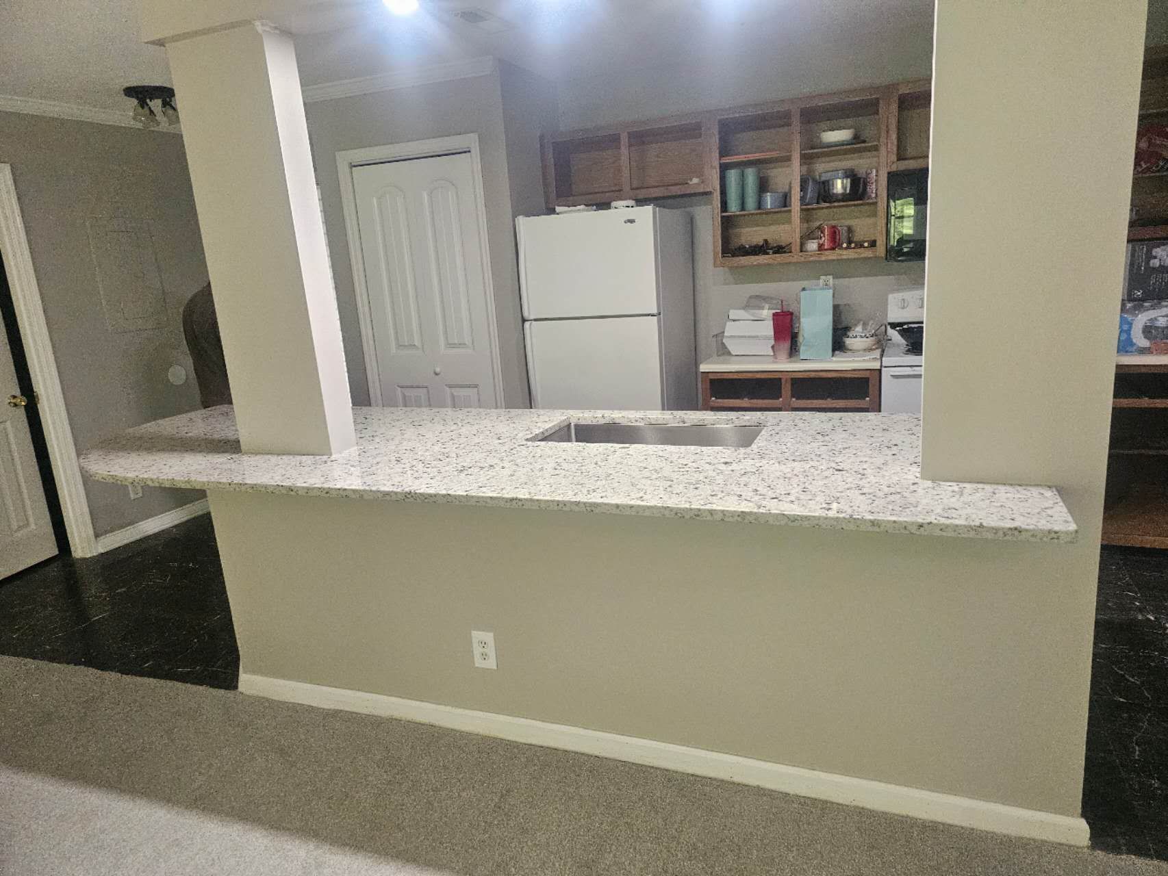 A kitchen with a refrigerator, sink, stove and cabinets.