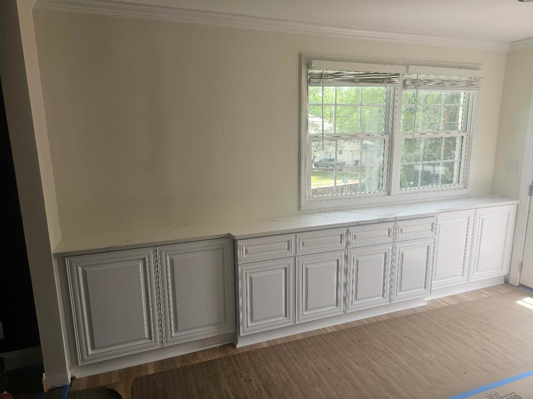 A living room with white cabinets and two windows.
