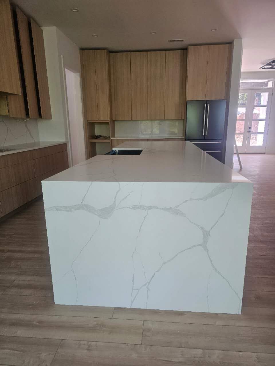 A kitchen with a large white island and wooden cabinets.