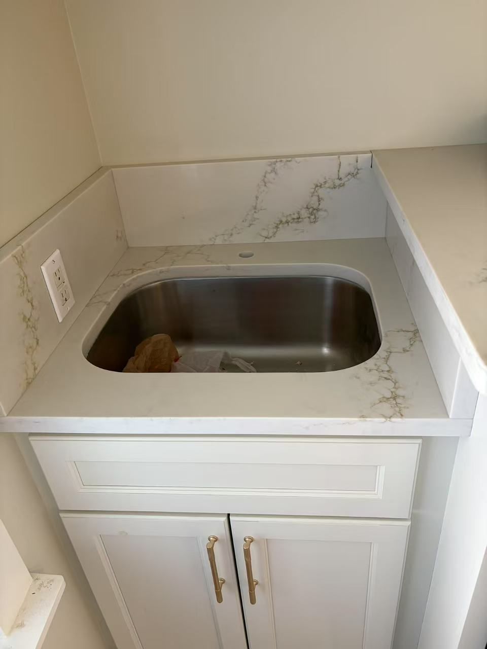 A stainless steel sink is sitting on top of a white counter.