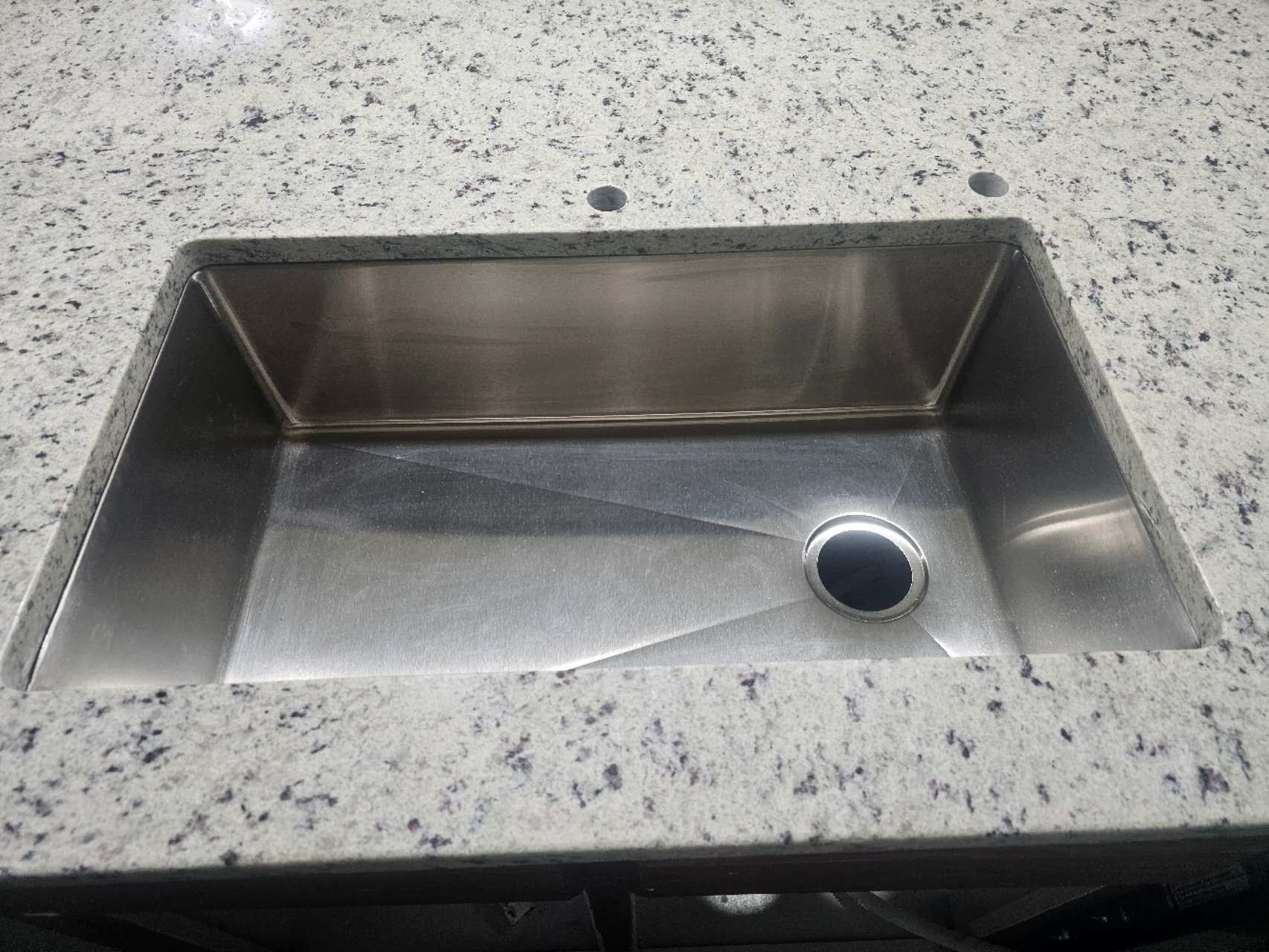 A stainless steel sink is sitting on top of a granite counter top.
