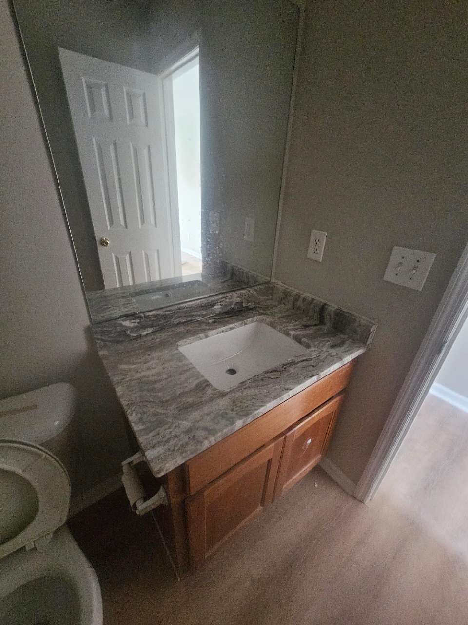 A bathroom with a sink, toilet, and mirror.