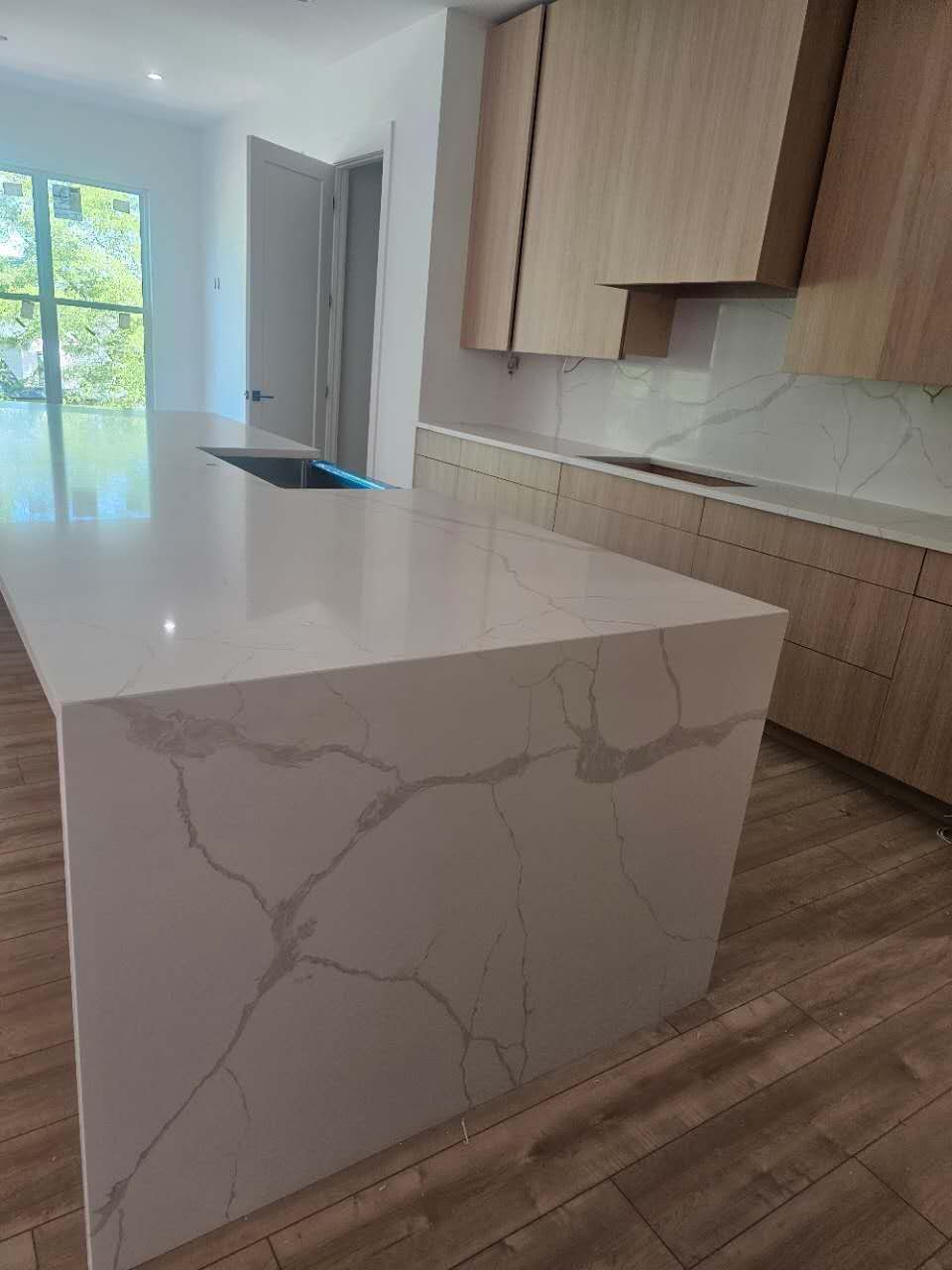 A kitchen with a large white counter top and wooden cabinets.