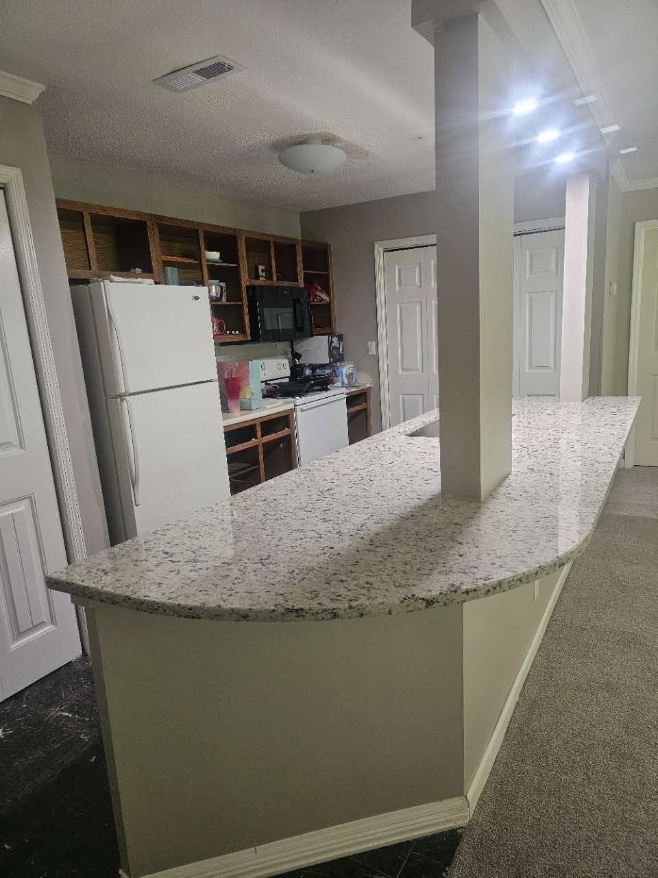 A kitchen with a large granite counter top and a refrigerator.