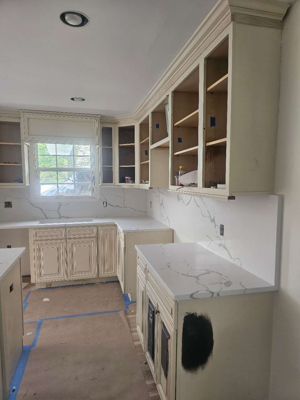 A kitchen with white cabinets and marble counter tops is being remodeled.