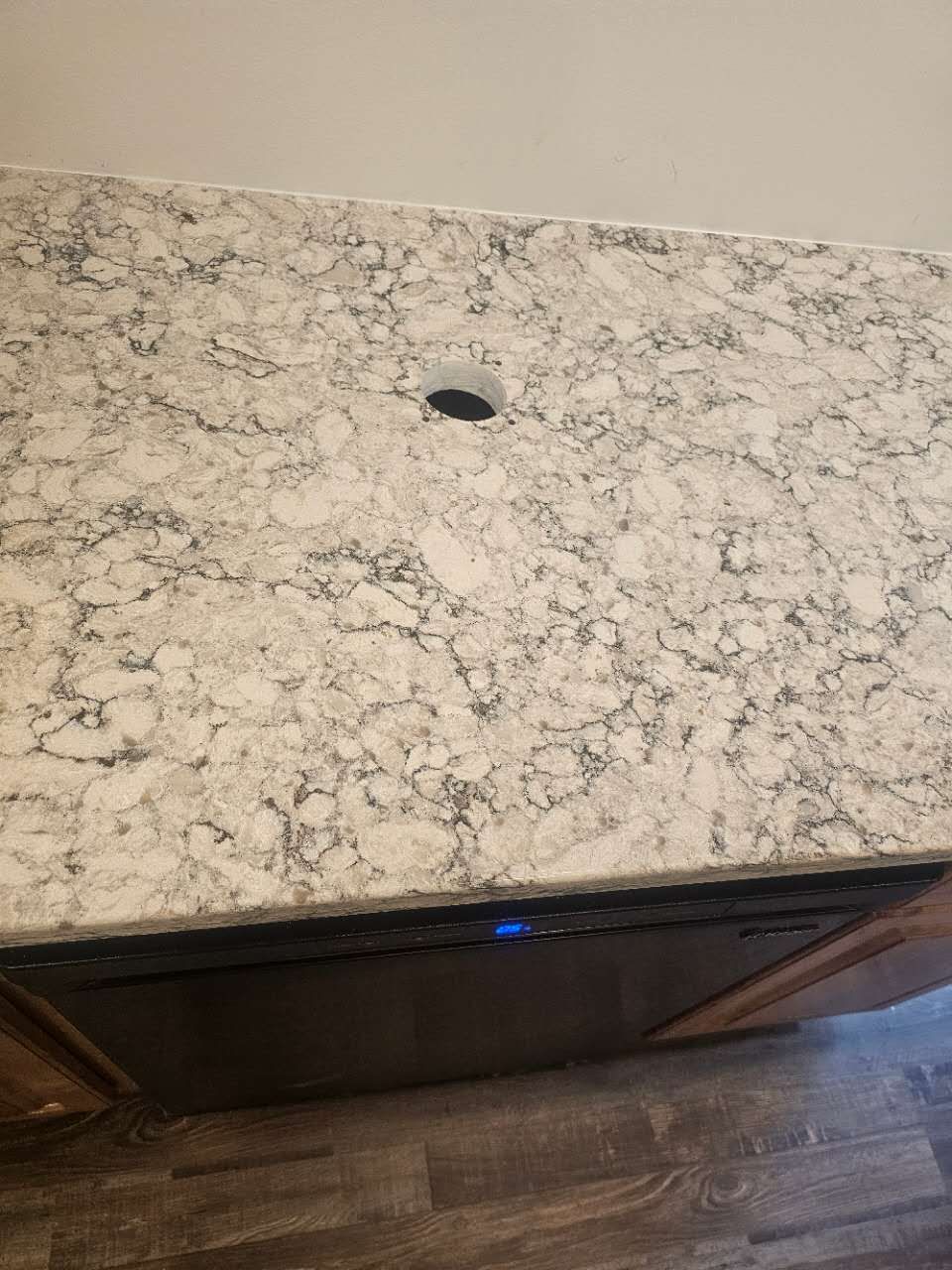 A kitchen counter with a hole in it and a dishwasher.