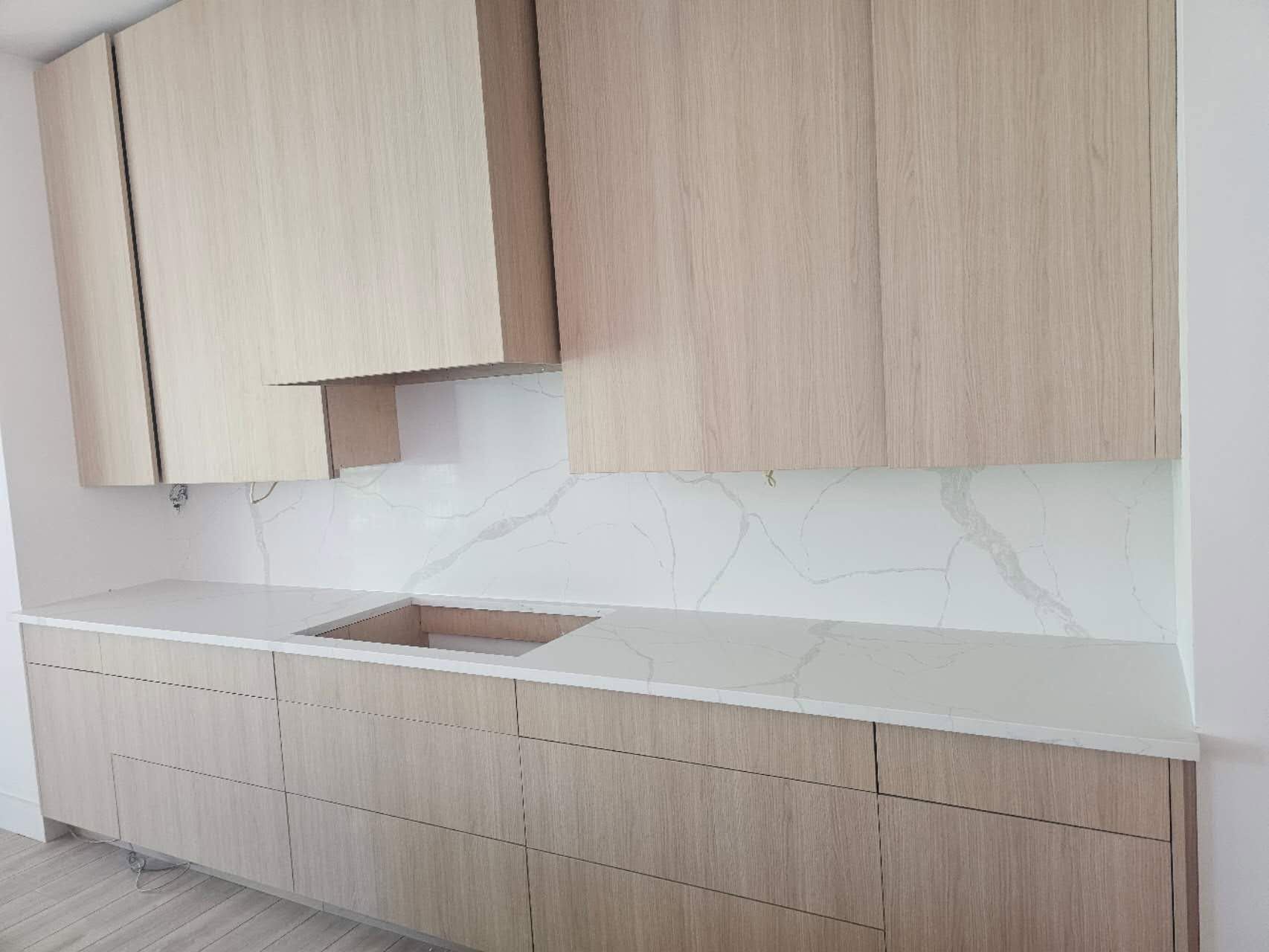 A kitchen with wooden cabinets and white counter tops.