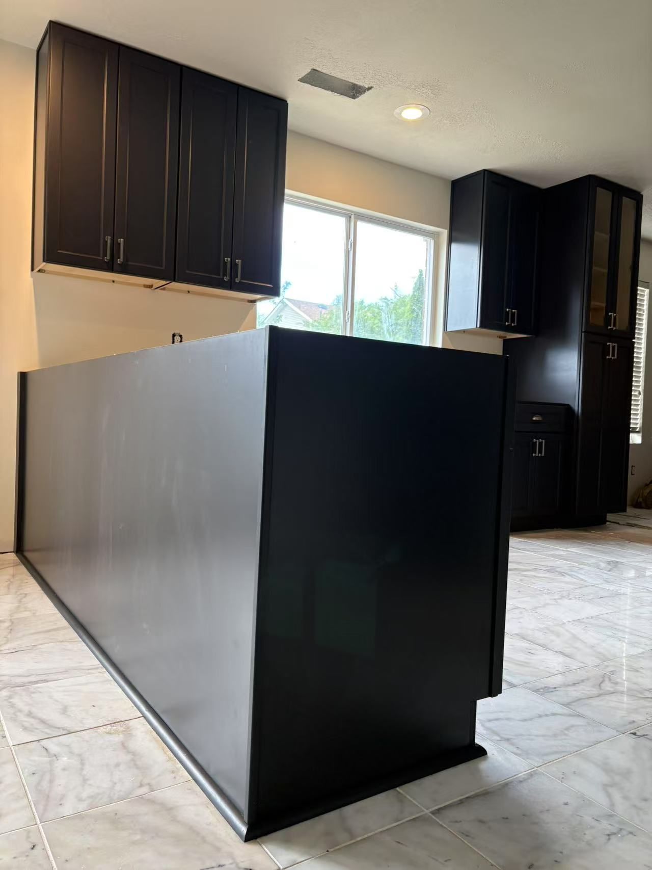A kitchen with black cabinets and a black island.