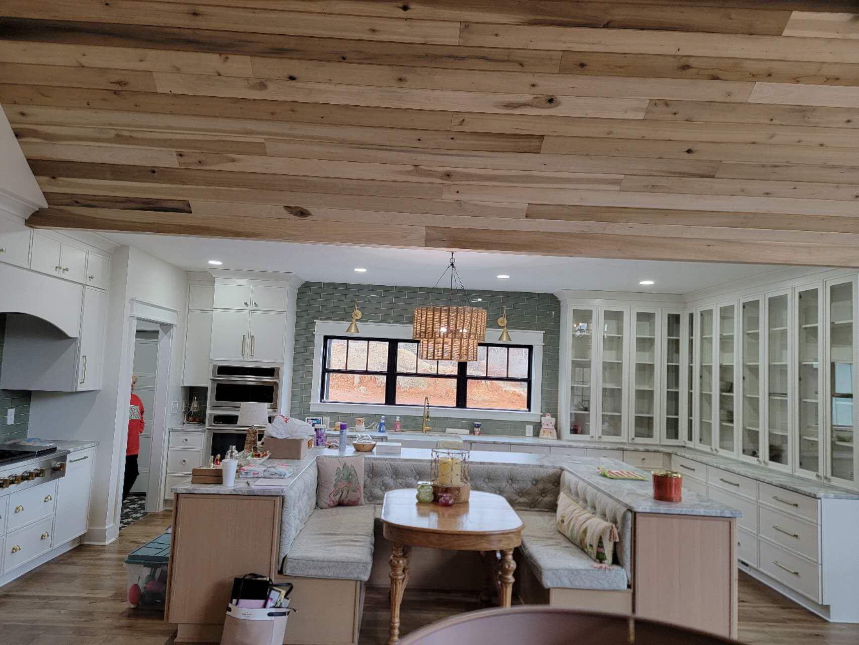 A kitchen with a wooden ceiling and a table and benches in it.