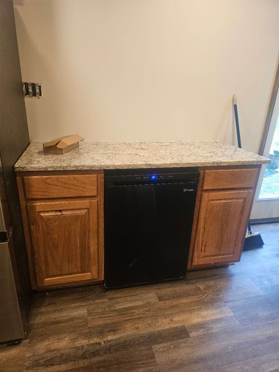 A kitchen with wooden cabinets and a black dishwasher.