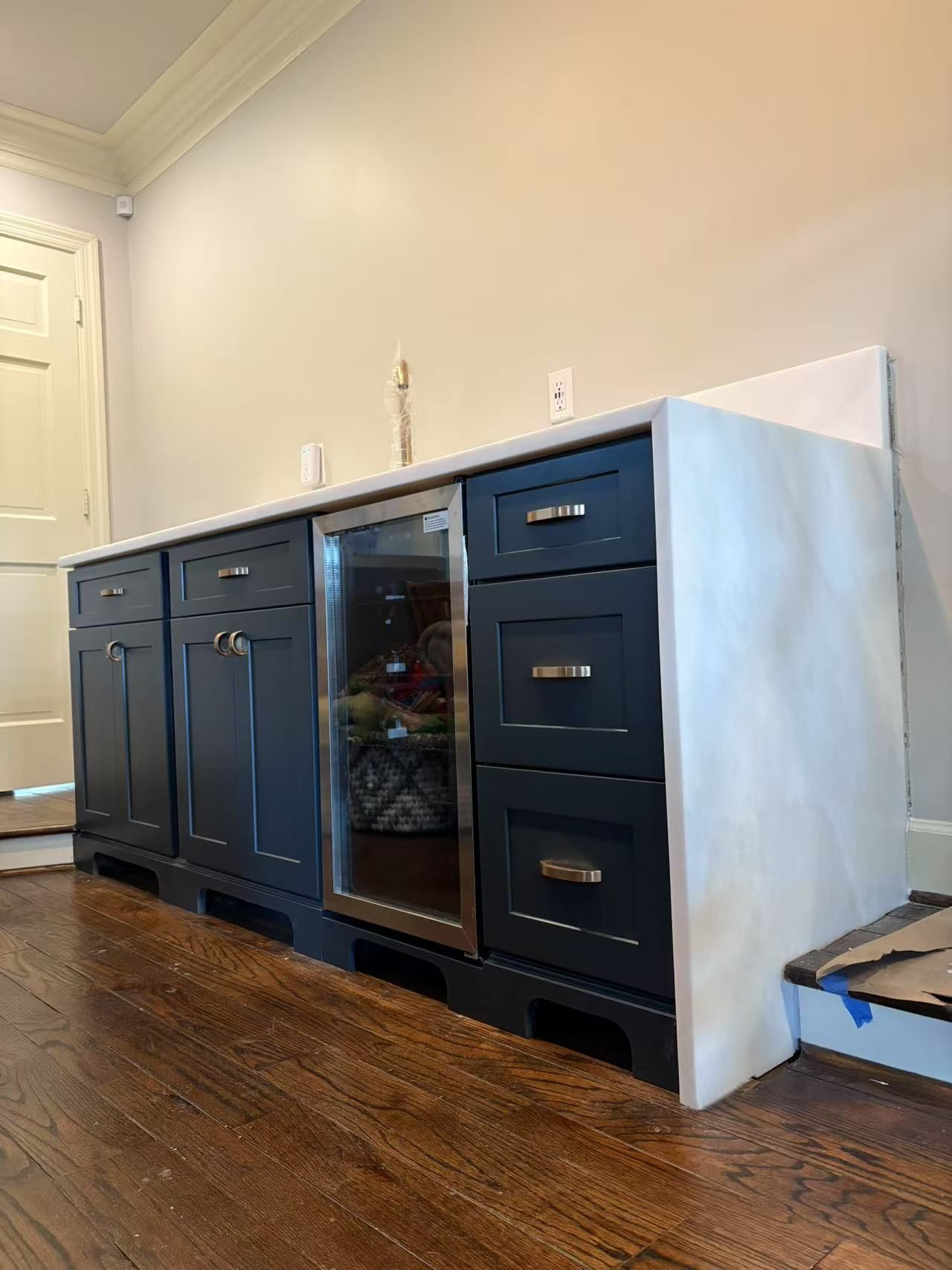 A kitchen with black cabinets and a stainless steel refrigerator.