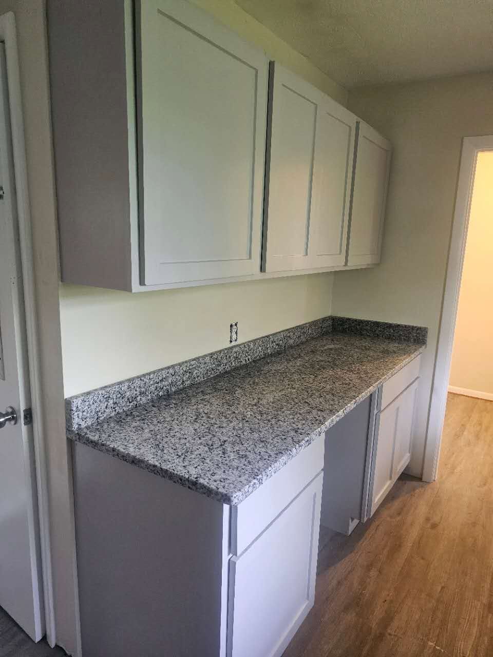 A kitchen with granite counter tops and white cabinets.