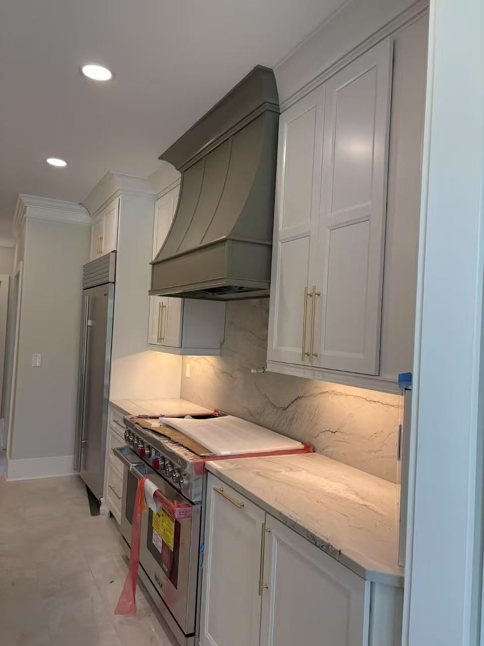 A kitchen with white cabinets, a stove, and a refrigerator.