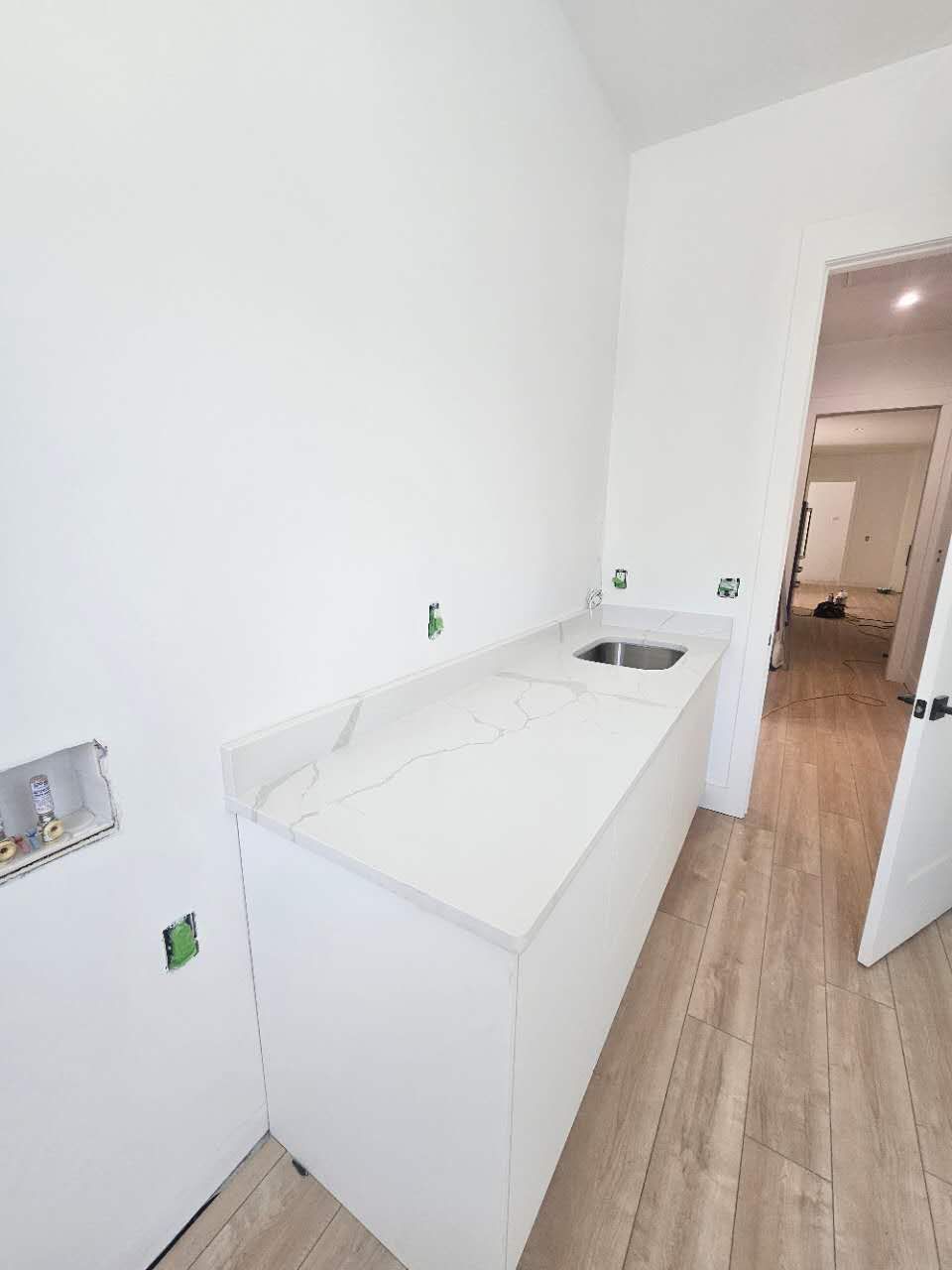 A kitchen with white cabinets and a sink in a house under construction.