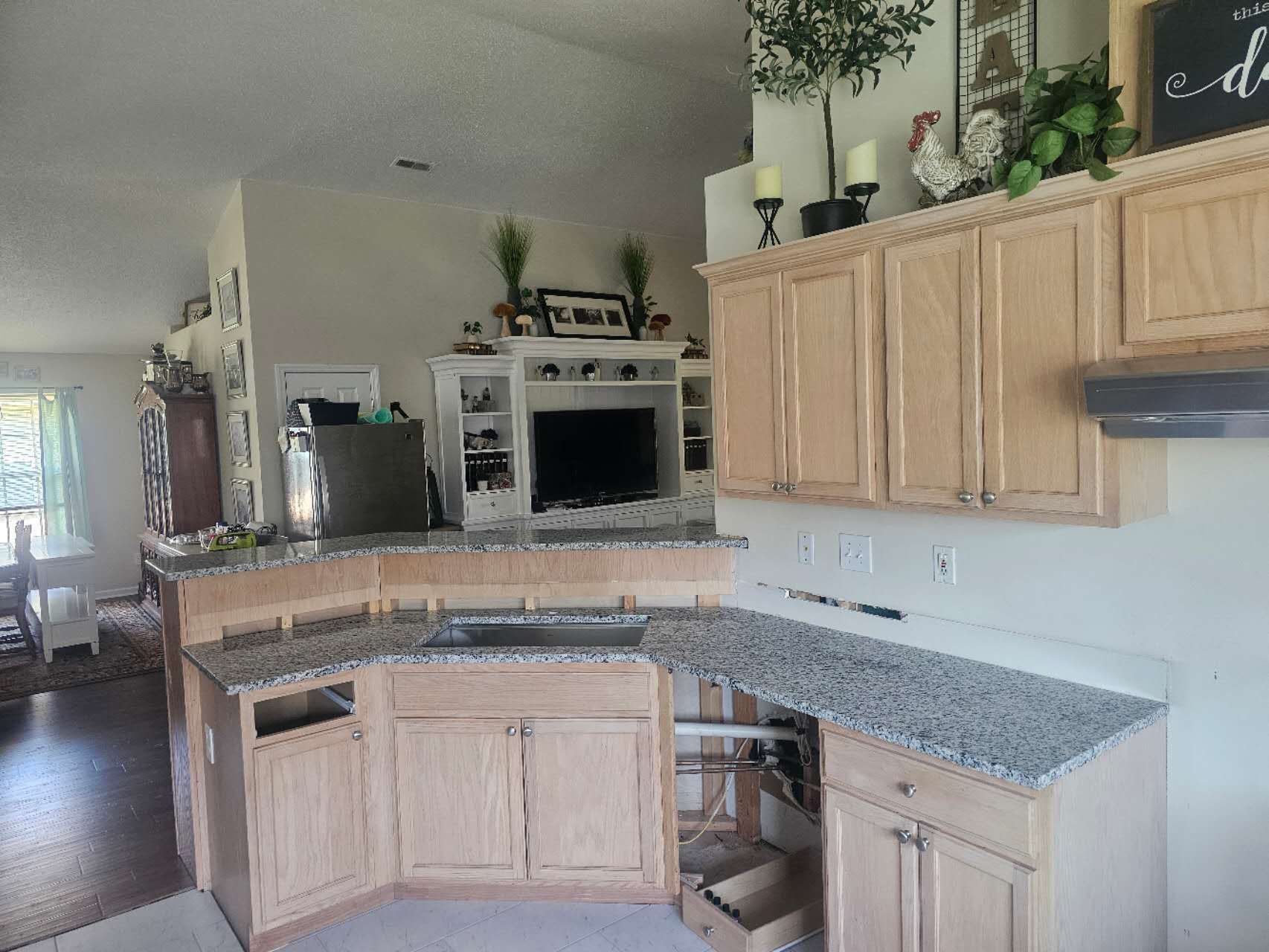 A kitchen with granite counter tops and wooden cabinets.