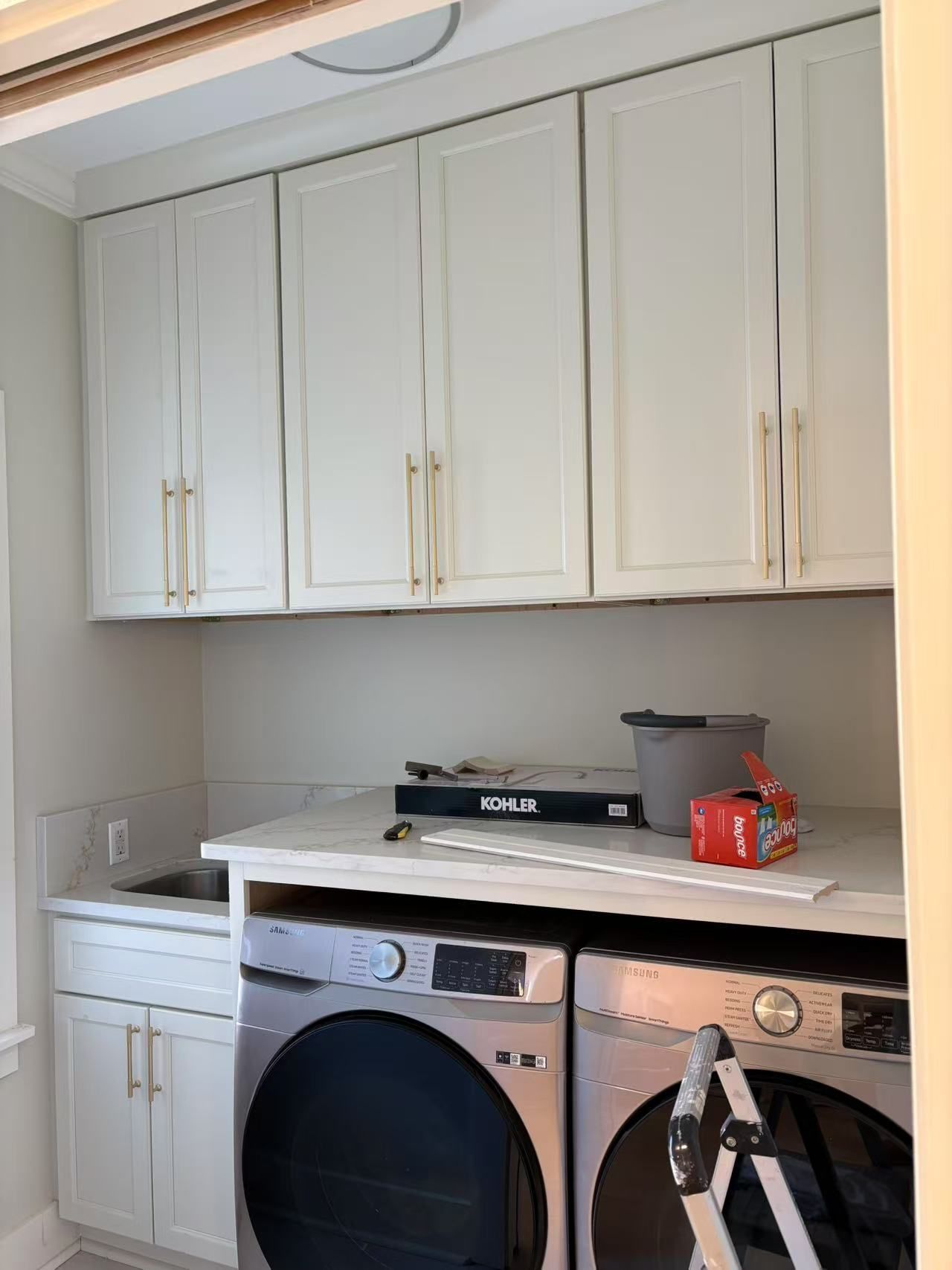 A laundry room with a washer and dryer and white cabinets.