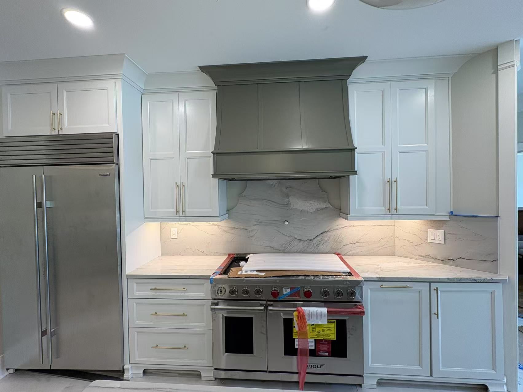 A kitchen with white cabinets, stainless steel appliances, and a refrigerator.