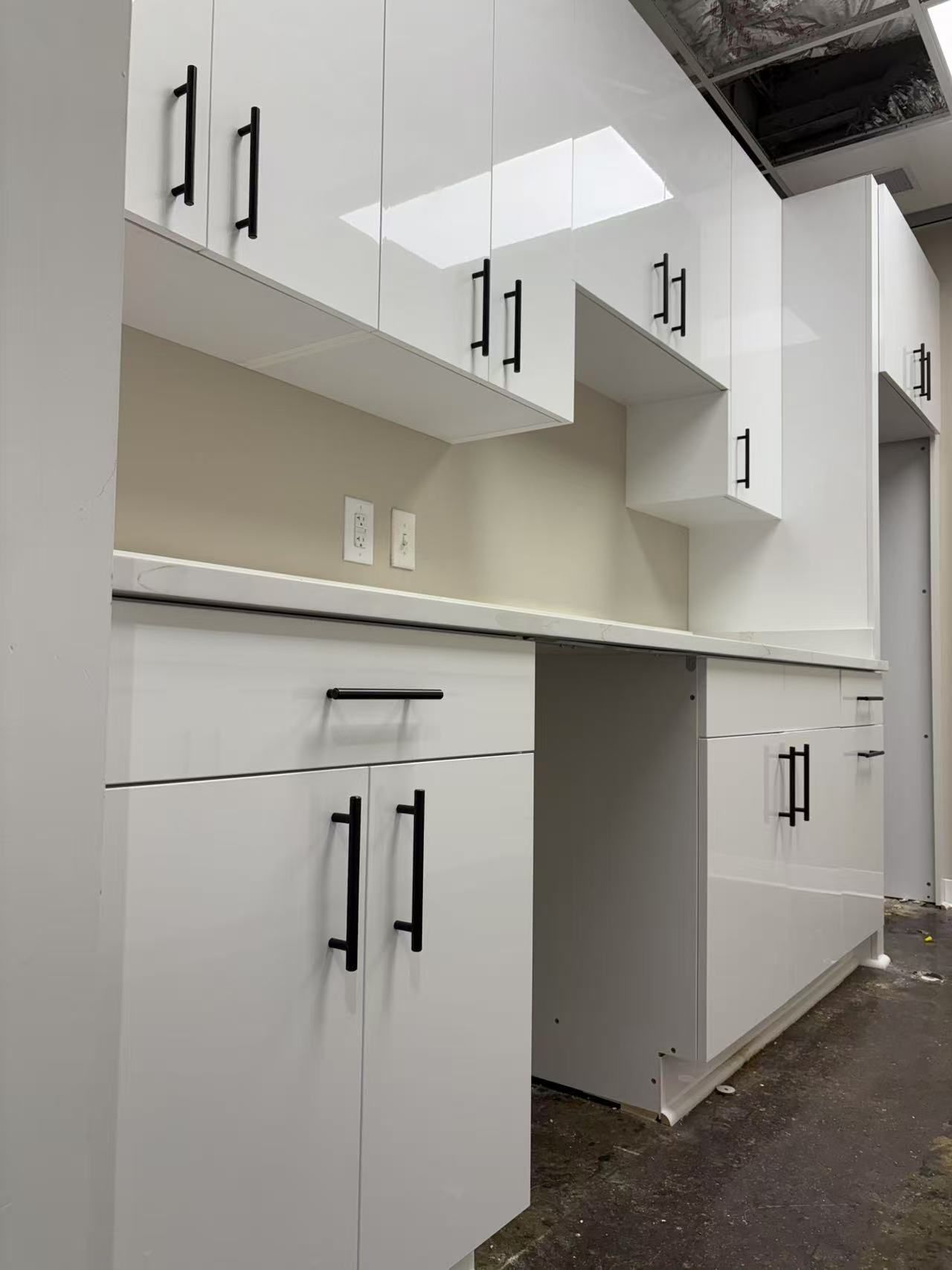 A kitchen with white cabinets and black handles.