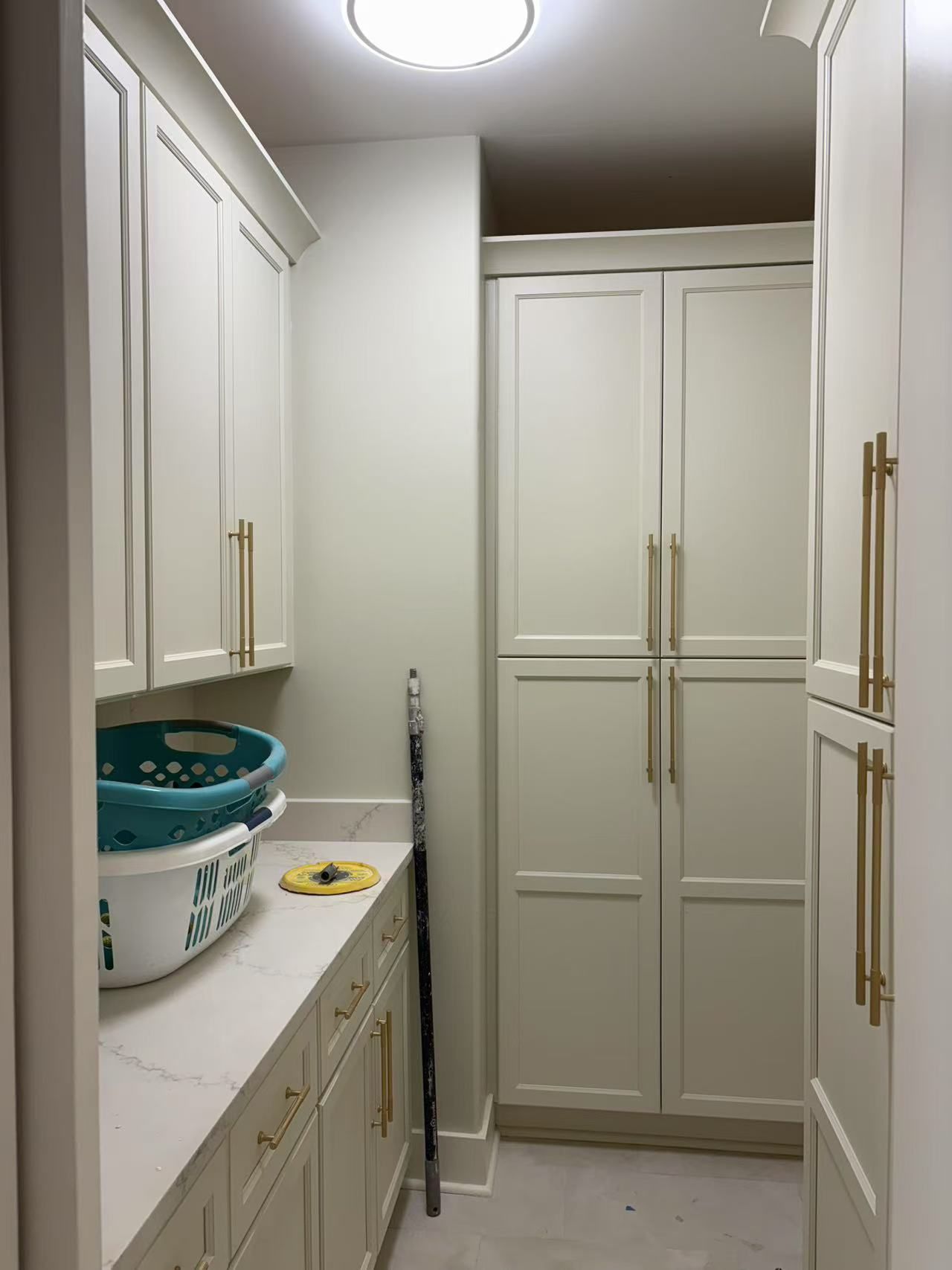 A laundry room with white cabinets and a basket on the counter.