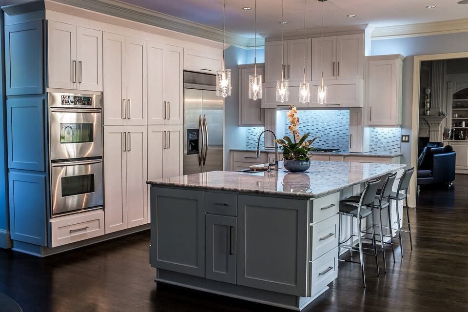 A kitchen with white cabinets, stainless steel appliances, and a large island.